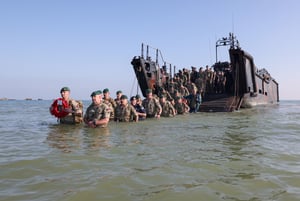 7 Commando Royal Marines make their way to the beach from a landing craft who will then begin a ‘yomp’ across the fields to their commemorative event in Port-en-Bassin to attend the annual Royal Marines D-Day commemorative service.